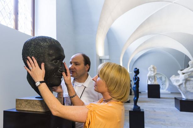 A woman and a man touching a head sculpture in the Albertinum museum in Dresden 